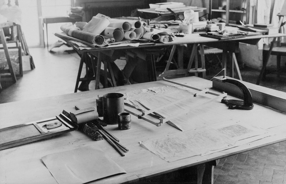 An architectural drafting table with construction blueprints and drawing tools spread across it.