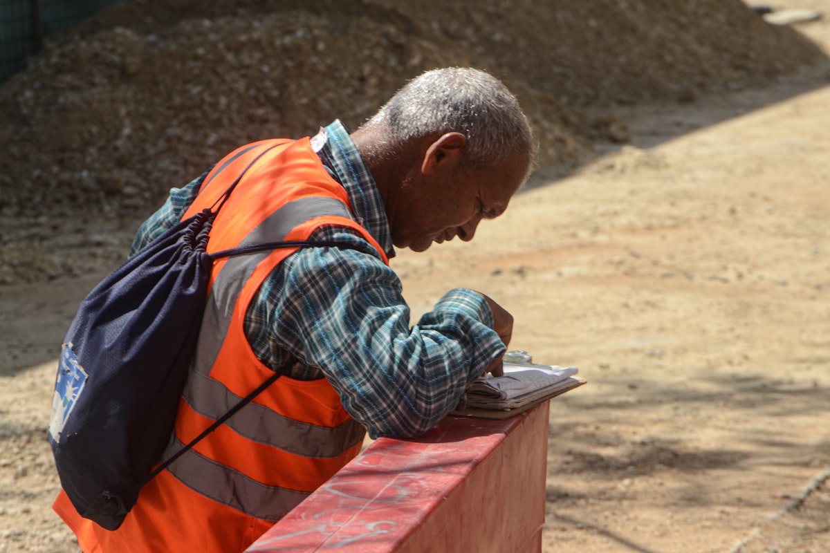 A general contractor estimator reviewing subcontractor bid letters and scope documents at an office desk covered with project drawings.