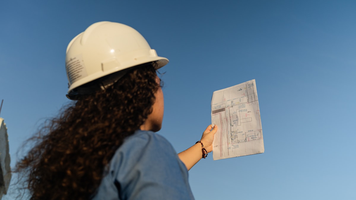 A general contractor estimator reviewing a stack of bid documents at a preconstruction office desk.
