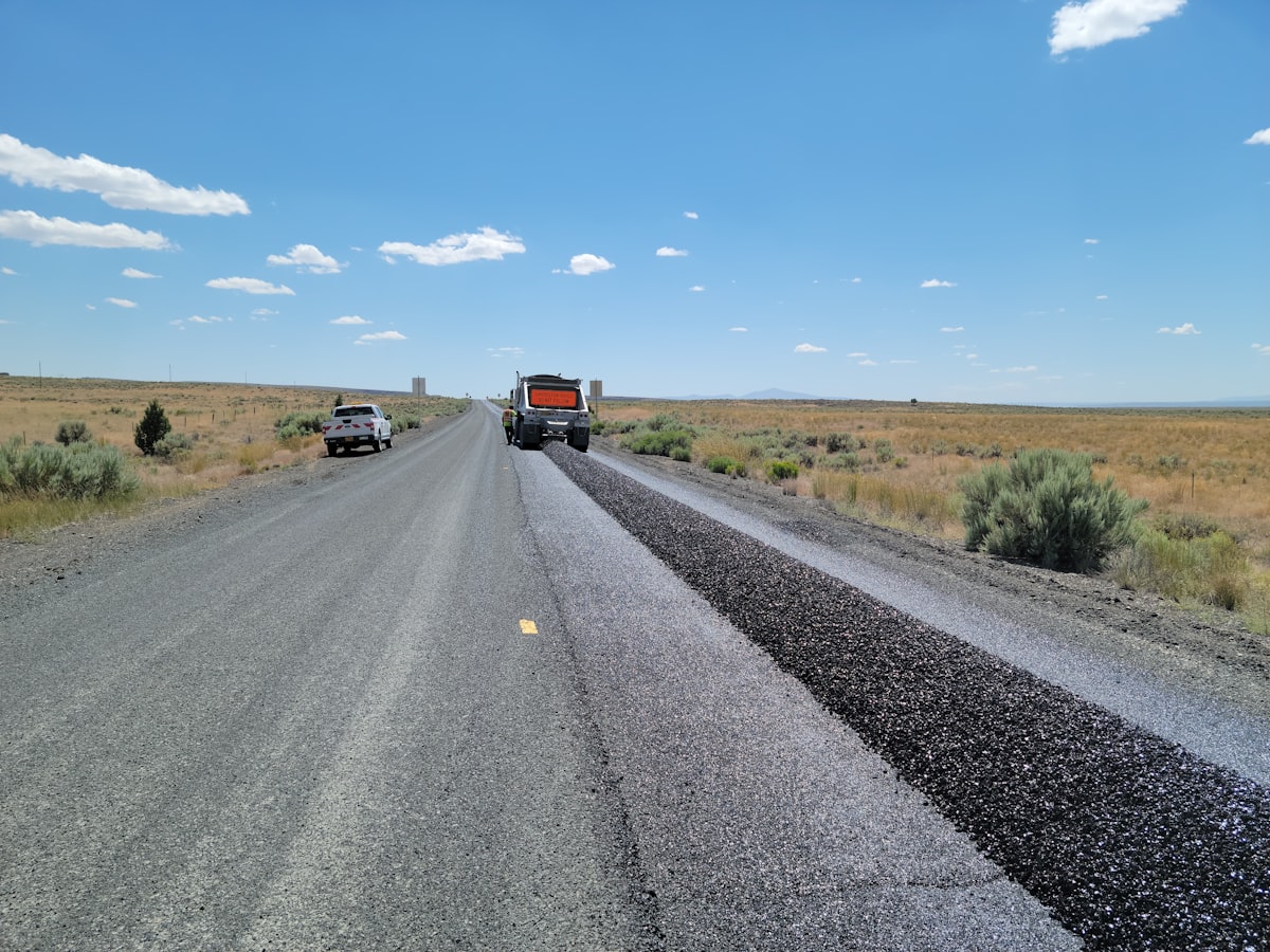 Heavy vibratory drum roller compacting asphalt on a large-scale highway infrastructure project.
