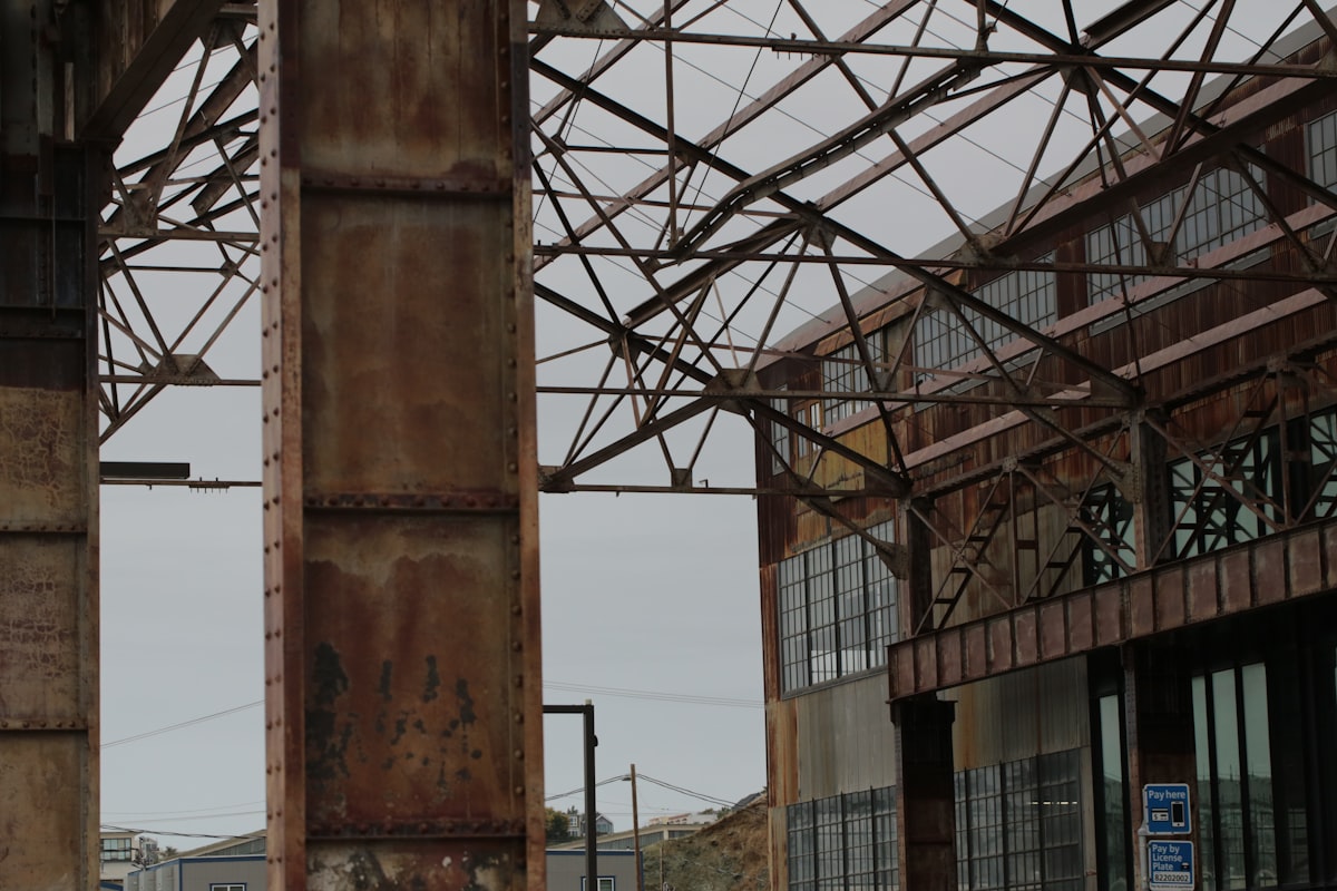 Steel beams stacked in a warehouse, representing the metals price escalation hitting construction material budgets in March 2026.