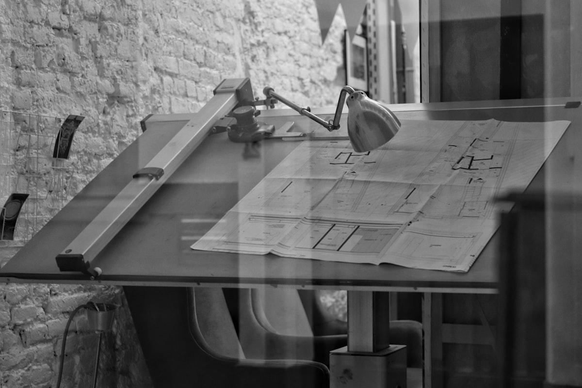 A general contractor estimator reviewing bid documents and cost estimates spread across a preconstruction office desk.