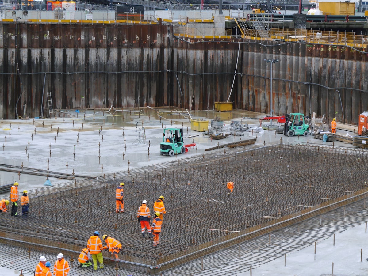 Construction workers reviewing plans on an urban job site, reflecting metro-level employment gains tracked in the January 2026 AGC analysis.