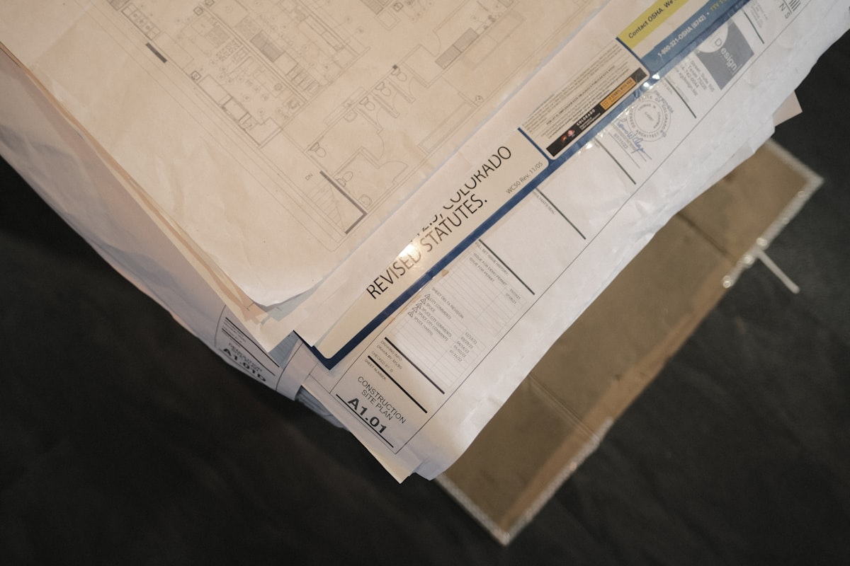 A GC estimator reviewing and comparing multiple subcontractor bid proposals spread across a desk during preconstruction.