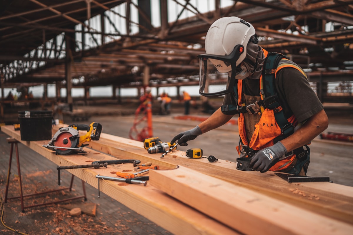 Workers in hard hats and safety vests participating in a hands-on construction skills training session at an outdoor facility.