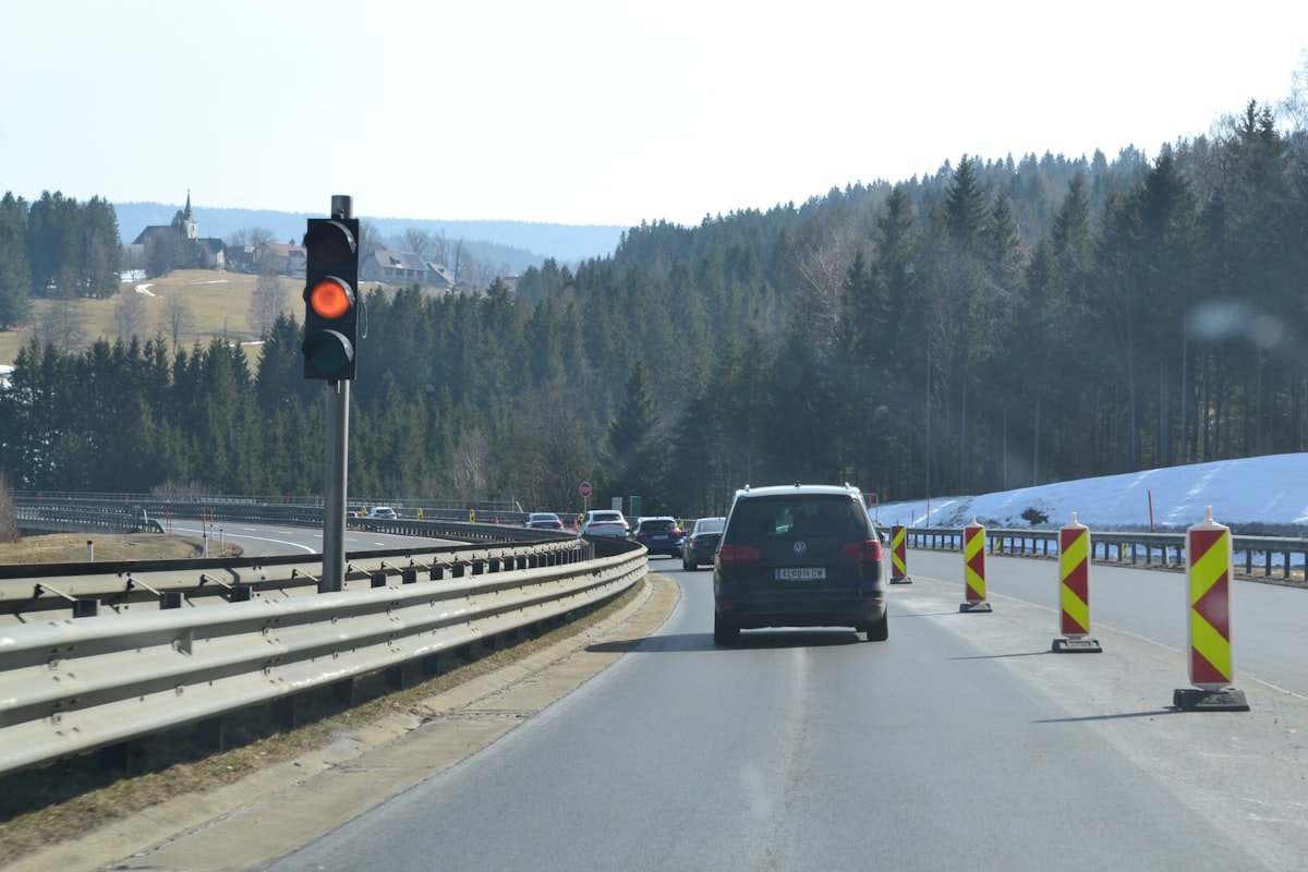 Construction crew working in a highway work zone with traffic barriers and safety signage visible.
