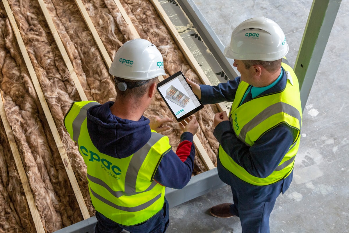 A GC estimator reviewing AI-assisted bid data on a tablet at a construction project office.