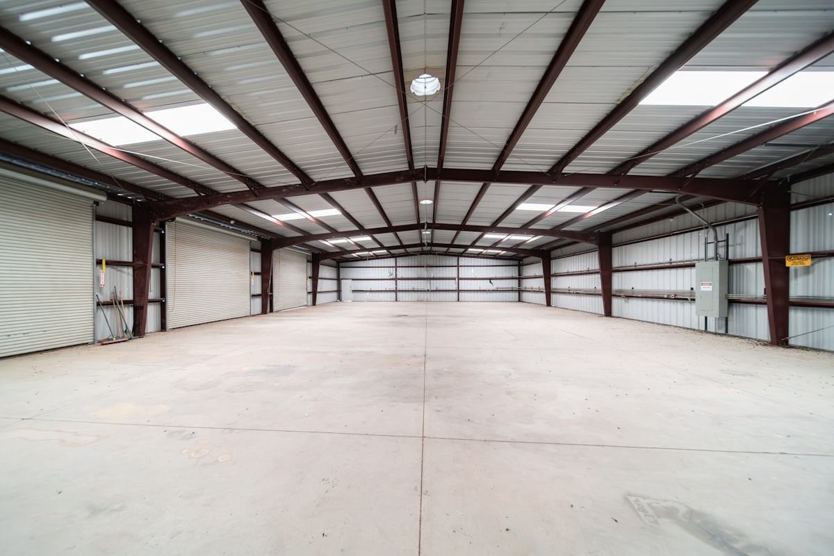 Stacked steel beams at a materials yard, representing surging construction input costs hitting GC estimators in mid-2026.